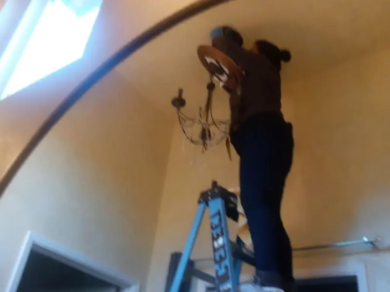 Electrician installing a chandelier in a Williamson residence